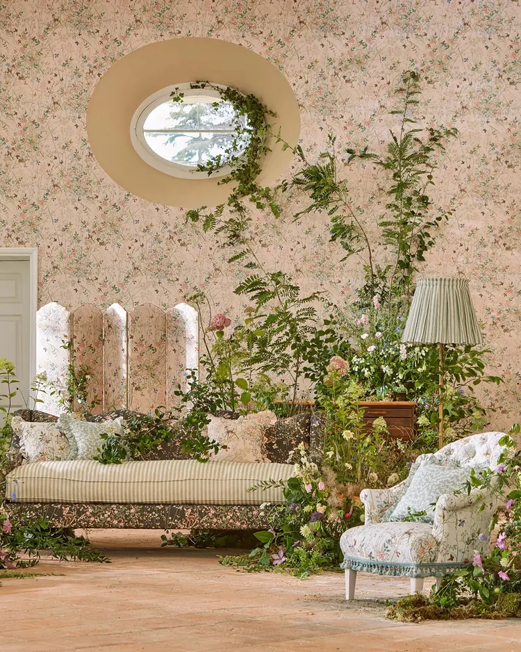 A beautifully styled interior featuring Sanderson floral wallpaper, botanical fabrics and vintage-inspired soft furnishings, with greenery and natural light creating a whimsical, enchanted room setting.